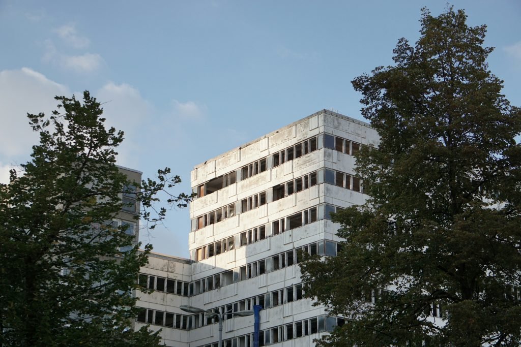 ein-hohes-weisses-gebaude-neben-baumen-0WKwizQjYrw