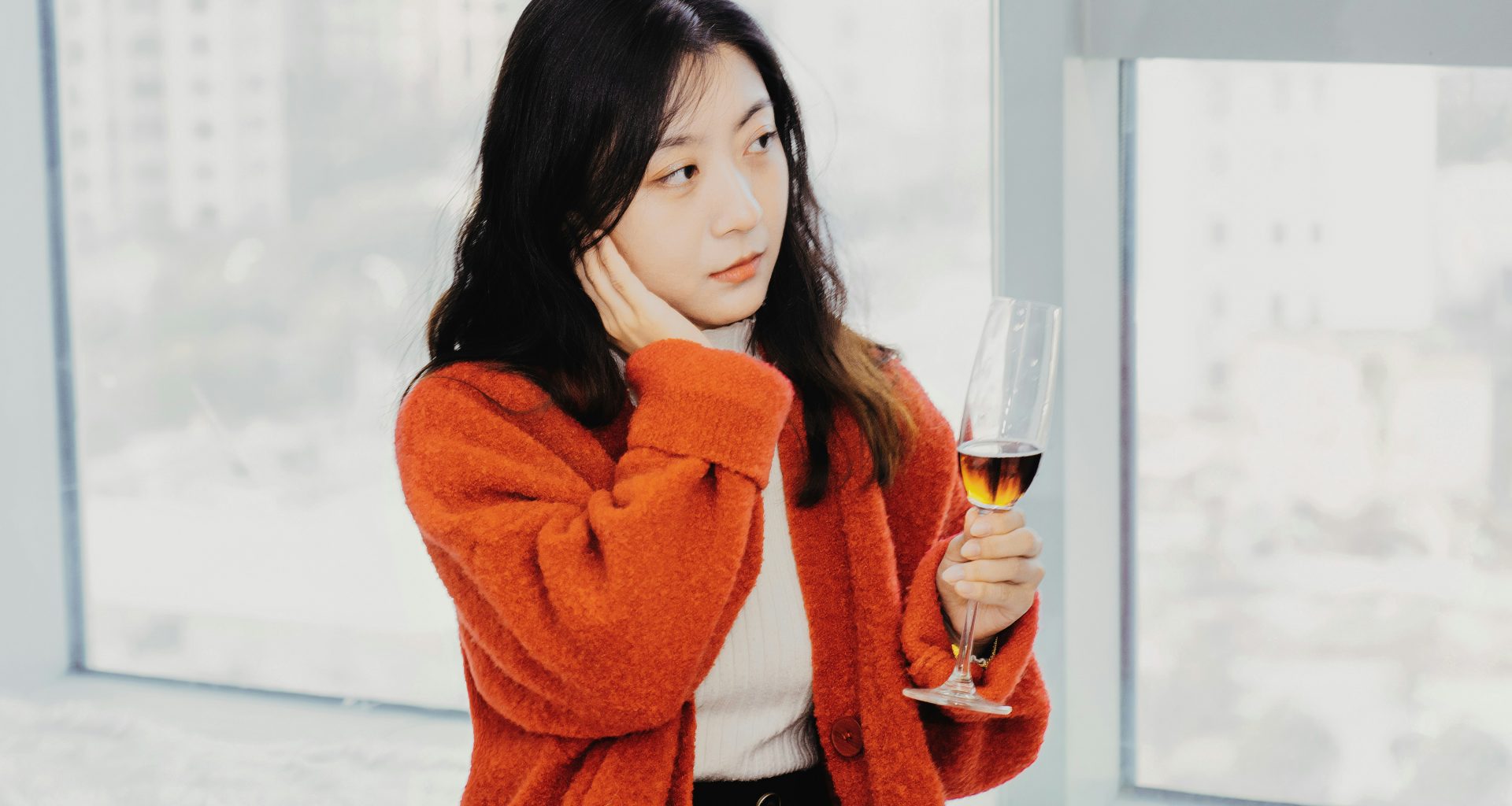 eine-frau-halt-ein-glas-wein-vor-einem-fenster-rdYPHtVbNTk