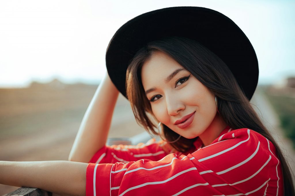 eine-frau-mit-hut-die-sich-auf-eine-schiene-stutzt-HKd41bxfslE