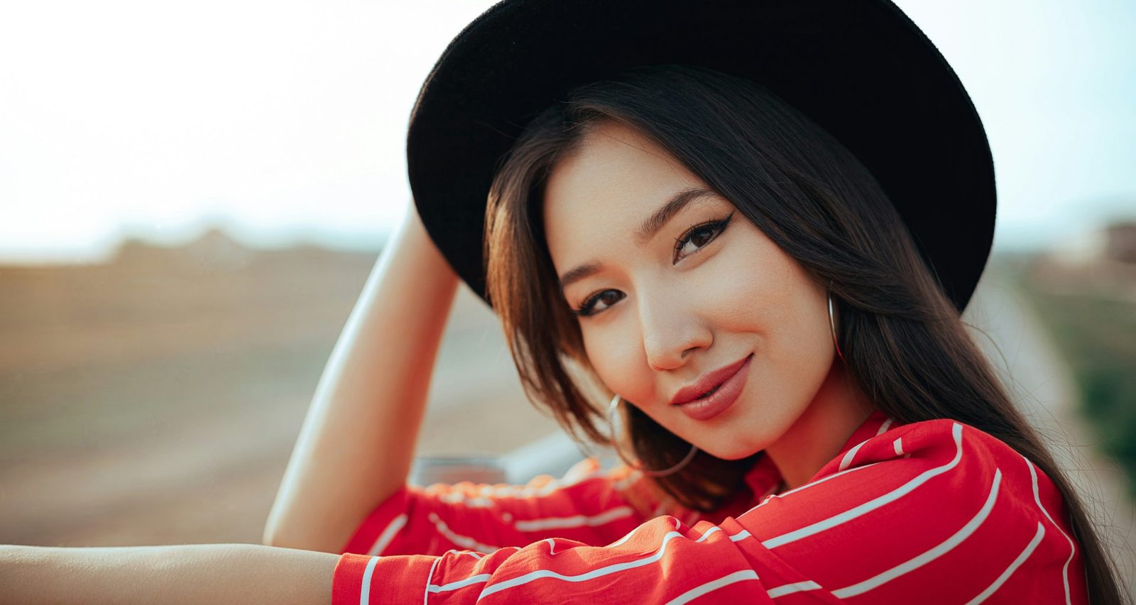 eine-frau-mit-hut-die-sich-auf-eine-schiene-stutzt-HKd41bxfslE