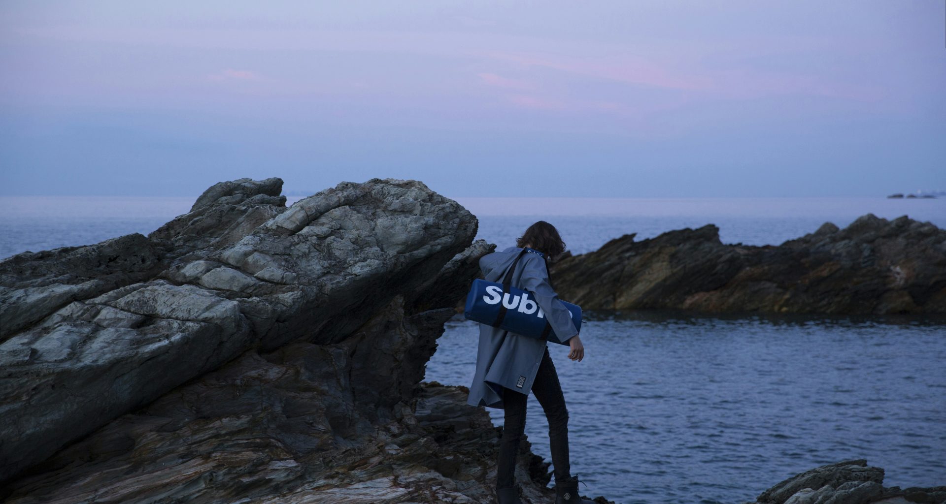 person-die-tasche-tragt-die-auf-einem-felsen-steht-sW_kKXX3H-Y