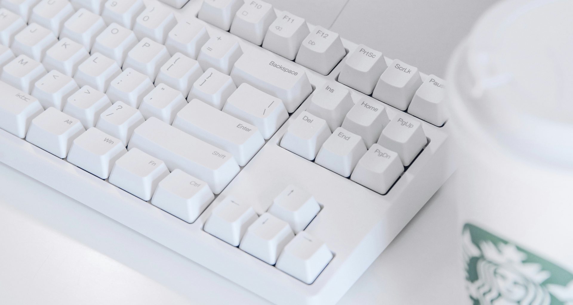 weisse-computertastatur-auf-weissem-tisch-e_J7i3eQEfo