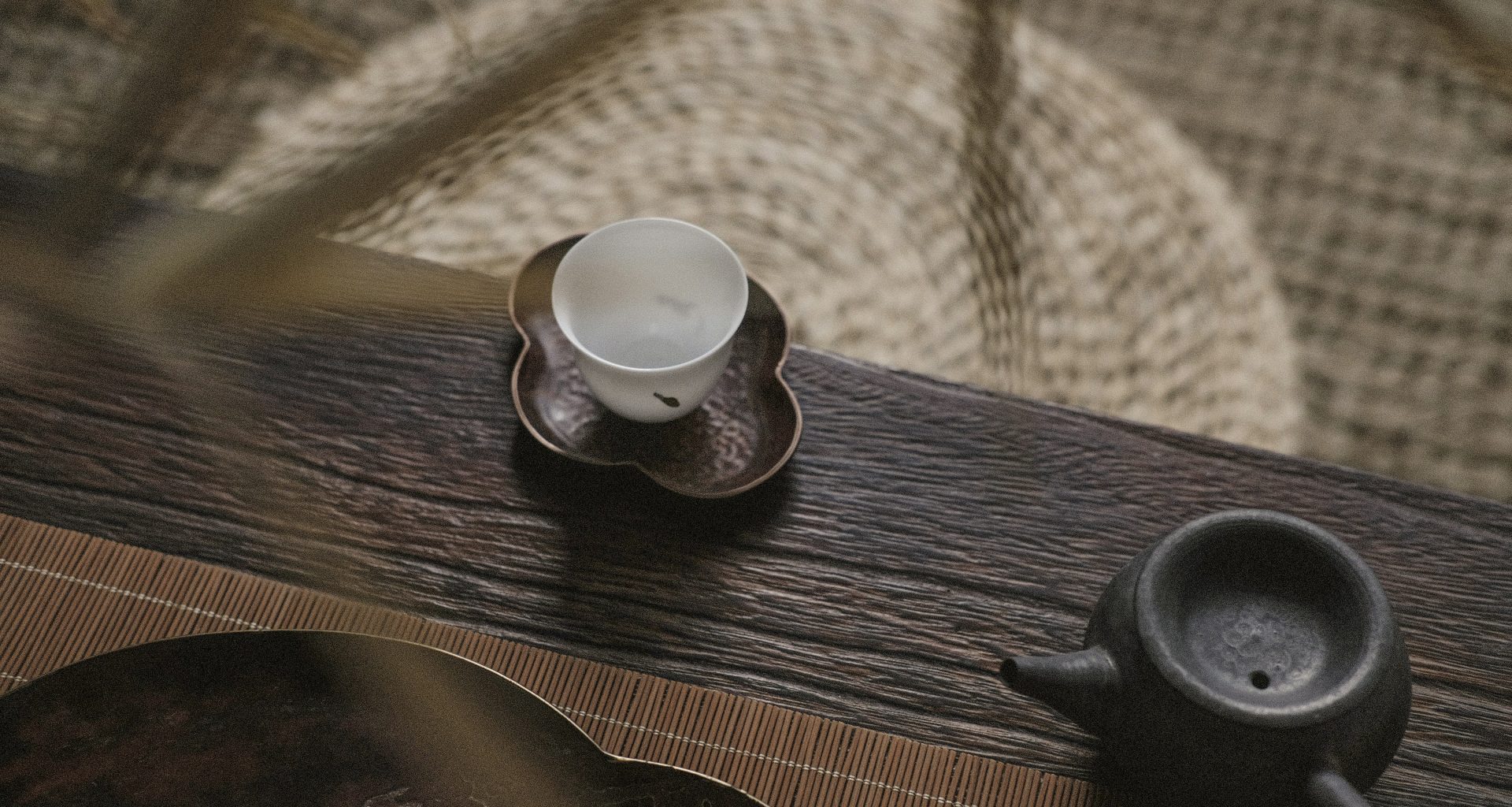 weisse-teetasse-auf-untertasse-in-der-nahe-der-teekanne-cmWUcVSJWOw