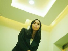 frau-im-schwarzen-mantel-in-der-nahe-der-weissen-wand-UjdL7YW9FWA