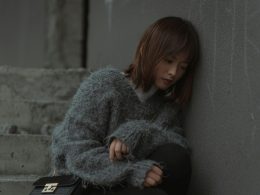 frau-im-grauen-pullover-sitzt-auf-grauer-betonbank-TncCMk2dQeQ