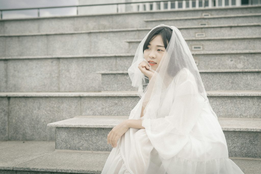 frau-im-weissen-kleid-sitzt-auf-einer-grauen-betontreppe-8s9nRchECyY