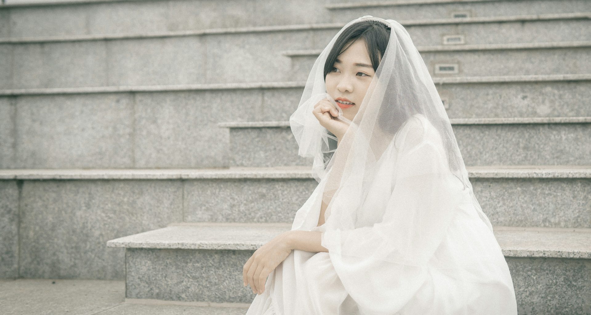 frau-im-weissen-kleid-sitzt-auf-einer-grauen-betontreppe-8s9nRchECyY