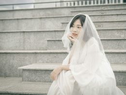 frau-im-weissen-kleid-sitzt-auf-einer-grauen-betontreppe-8s9nRchECyY