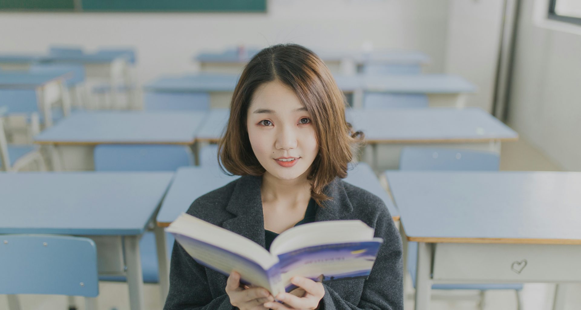 frau-die-ein-buch-liest-sitzt-auf-einem-stuhl-im-zimmer-i5nMmbr8JYg