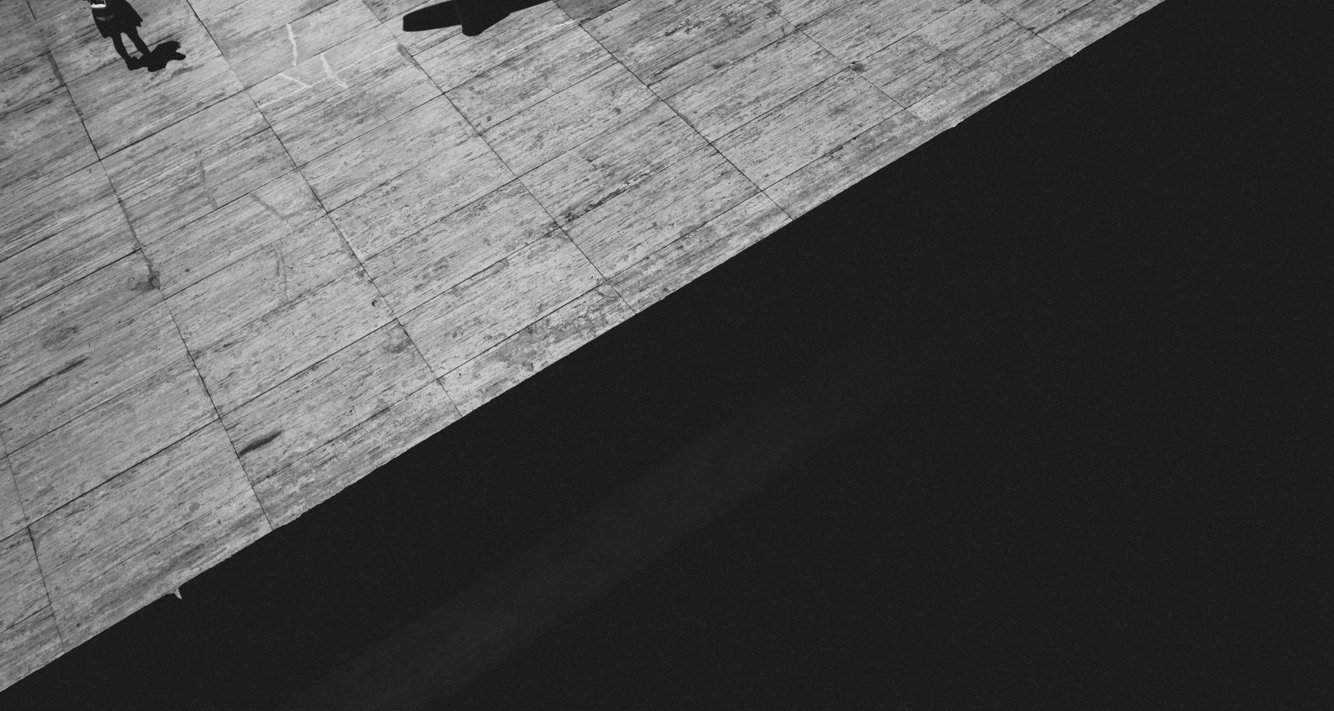 ein-schwarz-weiss-foto-einer-person-die-auf-einem-burgersteig-geht-cTtEiZxBUz8