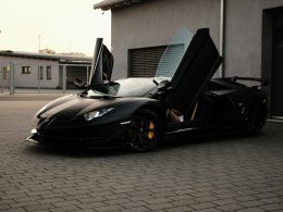 ein-schwarzer-sportwagen-der-vor-einer-garage-geparkt-ist-pSYNs4xFACc