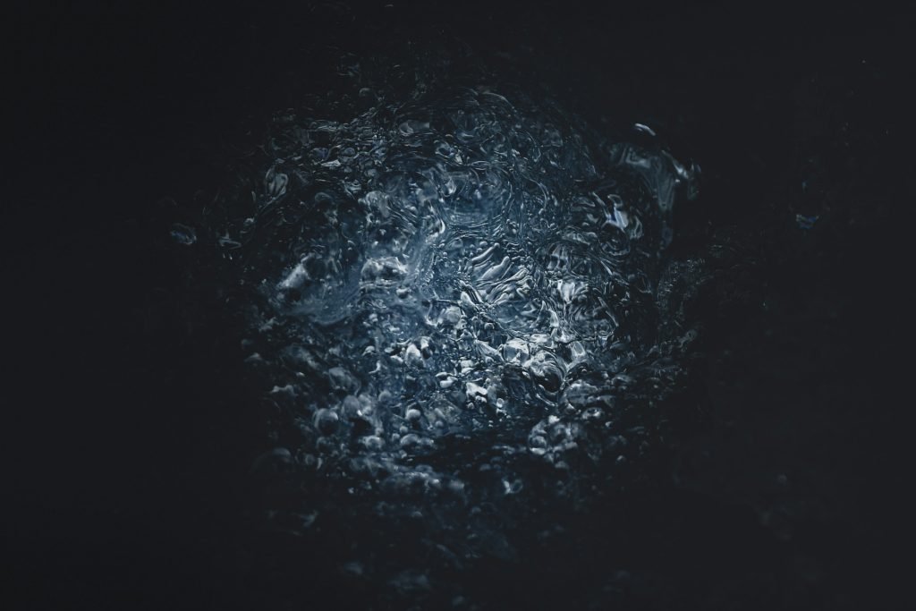 eine-nahaufnahme-einer-schwarzen-oberflache-mit-wasser-HSo-6tRqpTM