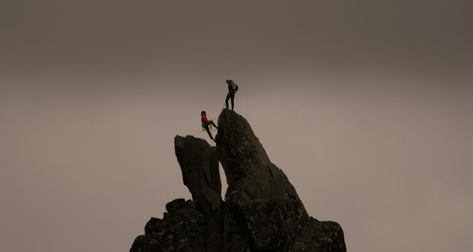 ein-paar-leute-klettern-auf-einen-felsen-jXjq7_Z-fpQ