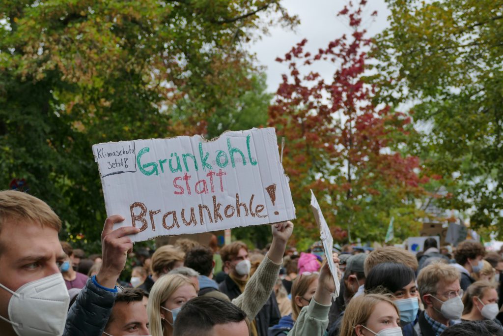 eine-gruppe-von-menschen-die-schilder-halten-und-masken-tragen-OaJUK1l-fW4