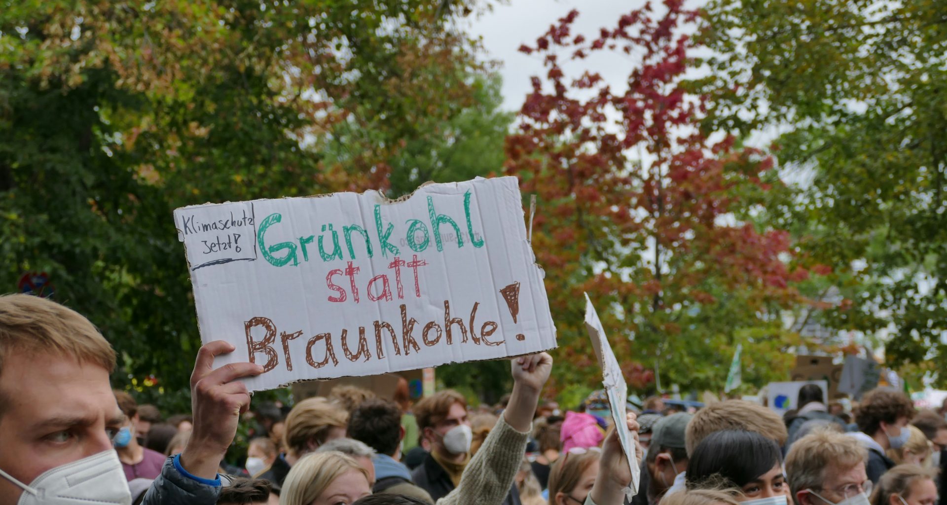 eine-gruppe-von-menschen-die-schilder-halten-und-masken-tragen-OaJUK1l-fW4