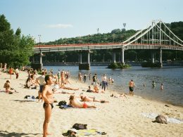 eine-gruppe-von-menschen-an-einem-strand-in-der-nahe-einer-brucke-88DWugInbA4