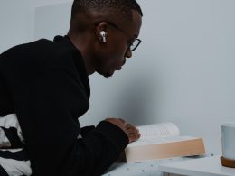 ein-mann-sitzt-an-einem-tisch-und-liest-ein-buch-KP0YnRwdlD8