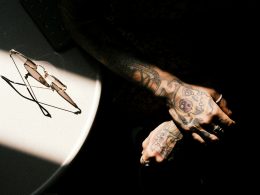 ein-mann-mit-tattoos-auf-dem-arm-neben-einem-tisch-kqDvRQa0JRI