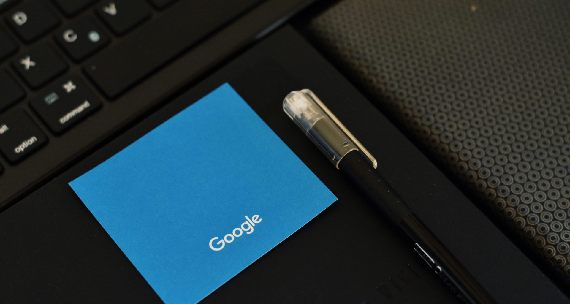 ein-stift-der-neben-einer-tastatur-auf-einem-notizbuch-sitzt-QSJymcYwtWY