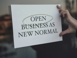 eine-person-die-ein-schild-halt-auf-dem-open-business-als-neue-normalitat-steht-abh7zBccJS8