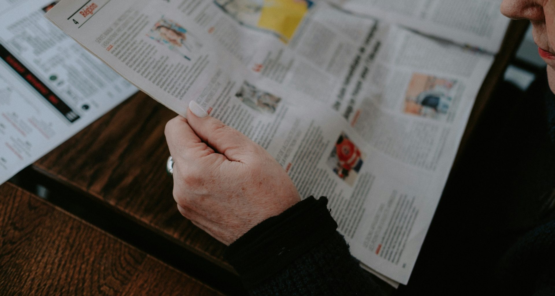 eine-person-die-an-einem-tisch-sitzt-und-eine-zeitung-liest-M1fG3il-cM4