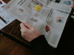 eine-person-die-an-einem-tisch-sitzt-und-eine-zeitung-liest-M1fG3il-cM4