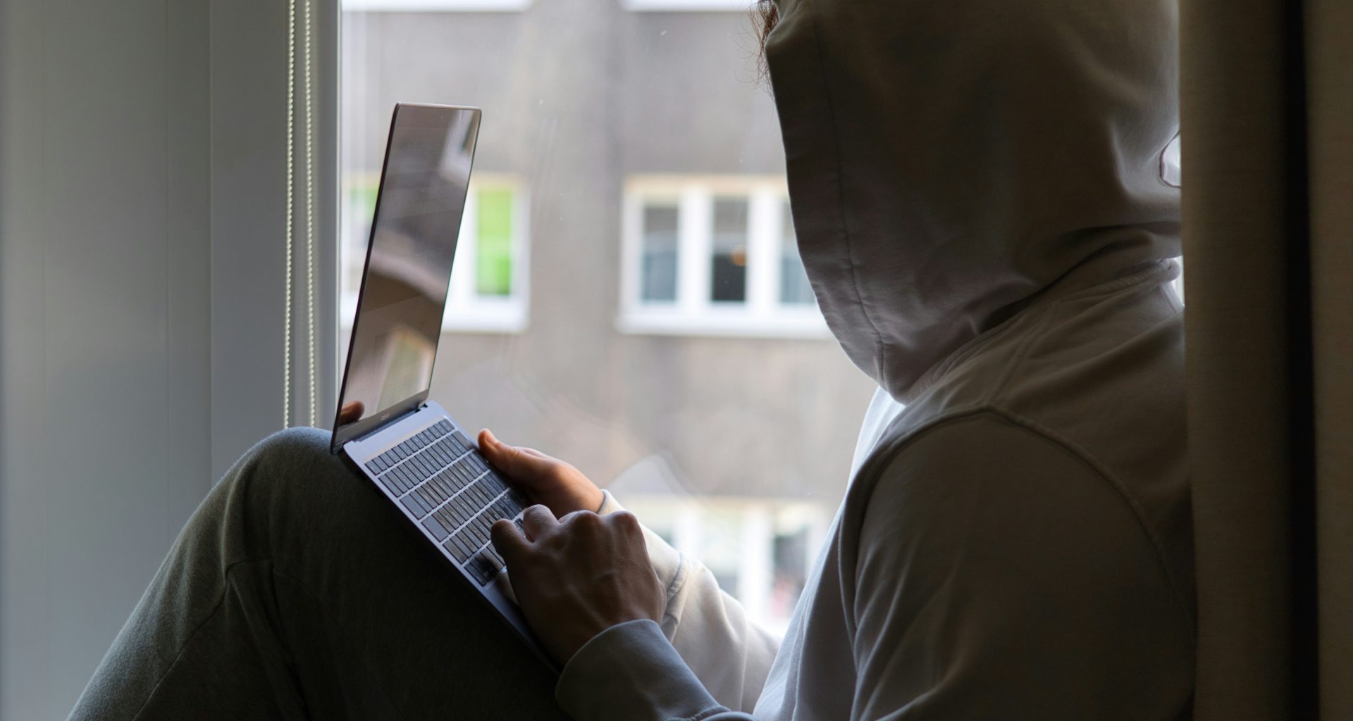 eine-person-die-mit-einem-laptop-auf-einer-fensterbank-sitzt-LUkBIQ2nwvg