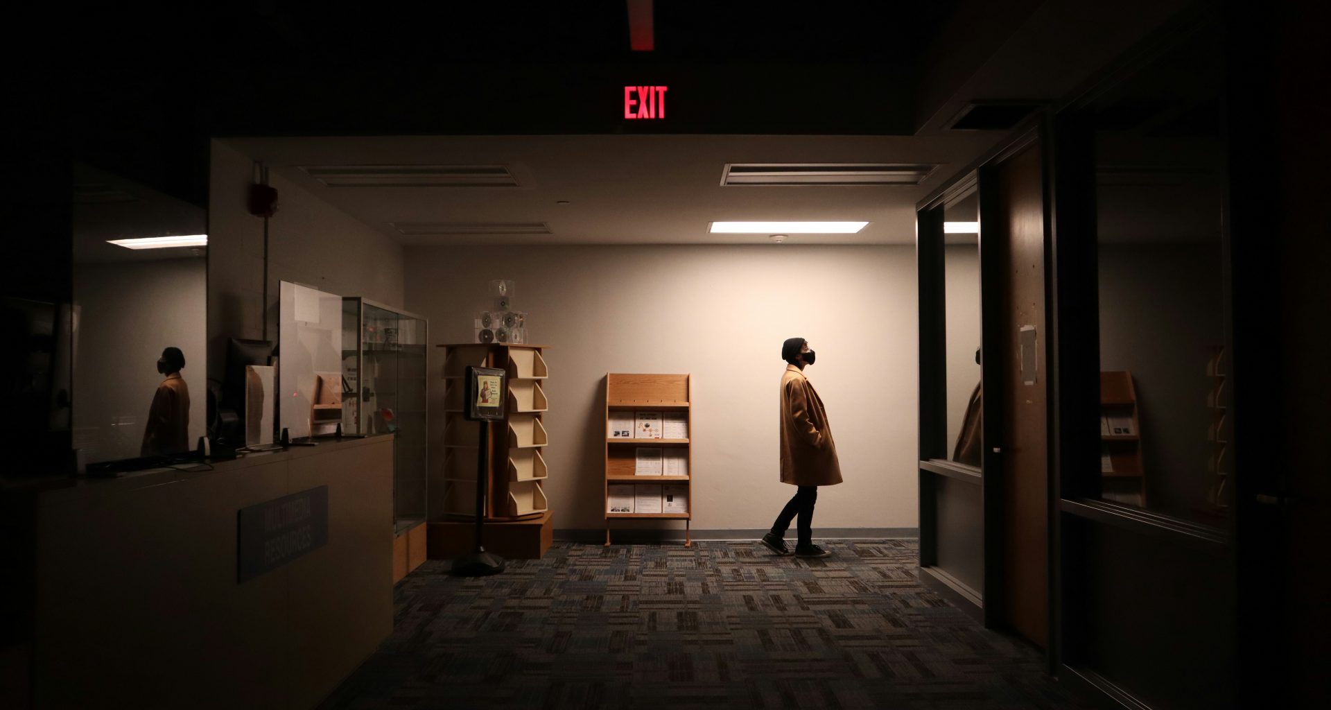 eine-person-die-in-einem-dunklen-raum-einen-flur-entlang-geht-J5i_bmA7xoY