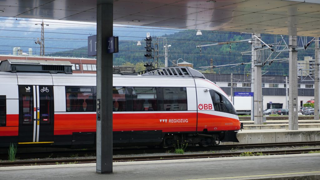 ein-rot-weisser-zug-der-an-einem-bahnhof-vorbeifahrt-tIqeWWi1nfQ