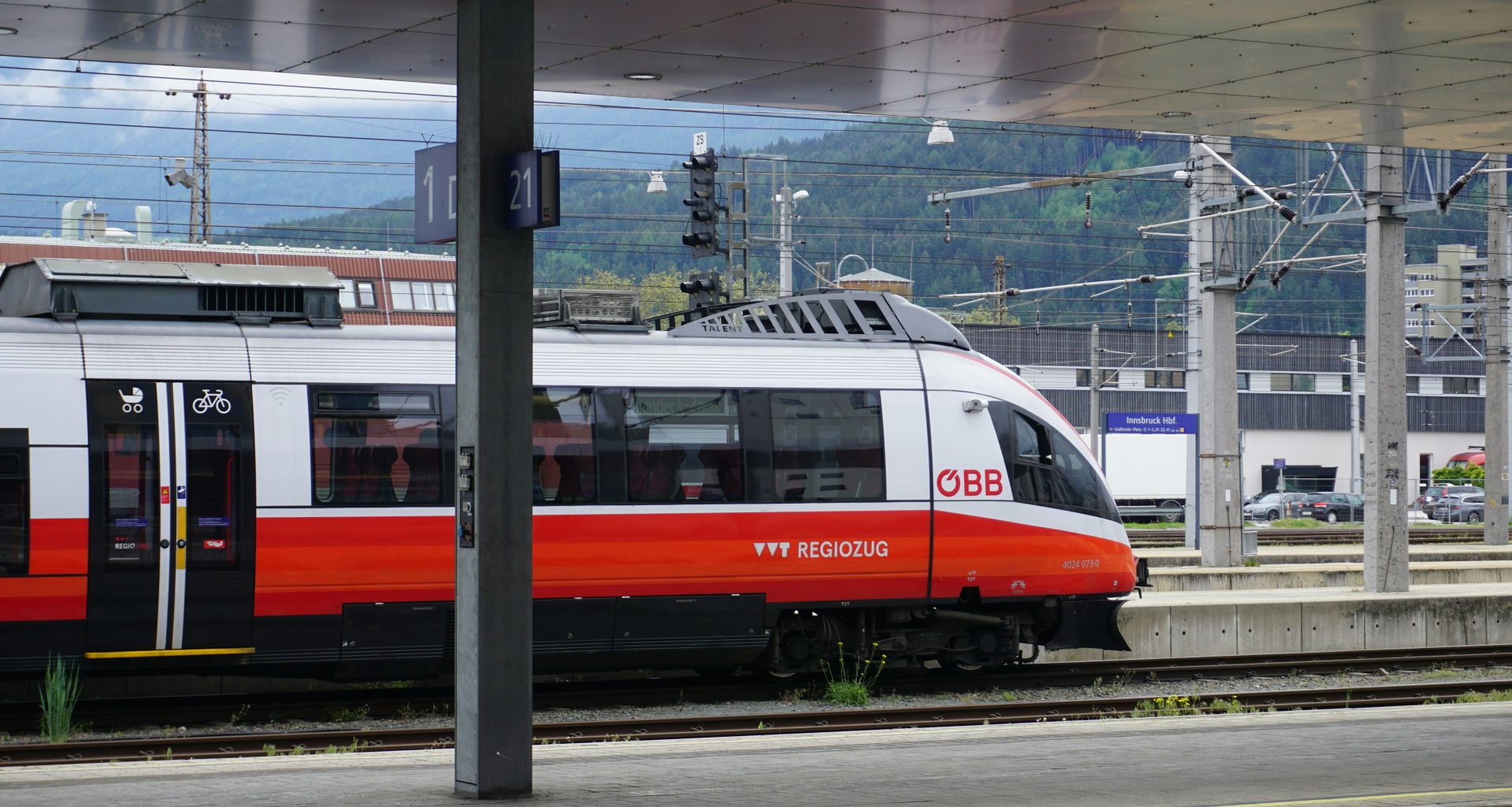 ein-rot-weisser-zug-der-an-einem-bahnhof-vorbeifahrt-tIqeWWi1nfQ