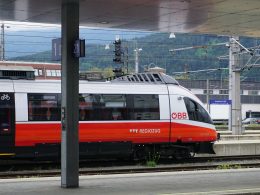 ein-rot-weisser-zug-der-an-einem-bahnhof-vorbeifahrt-tIqeWWi1nfQ