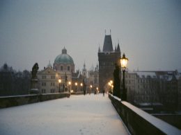 ein-verschneiter-gehweg-mit-einer-strassenlaterne-und-gebauden-im-hintergrund-0aDCezTFkVU