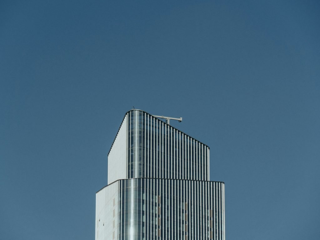 ein-hohes-gebaude-mit-einem-flugzeug-das-am-himmel-fliegt-zyfxfeTXCfU