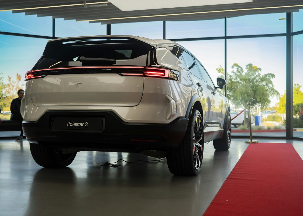 ein-weisses-auto-das-vor-einem-grossen-fenster-geparkt-ist-8l9I2JBBcmY