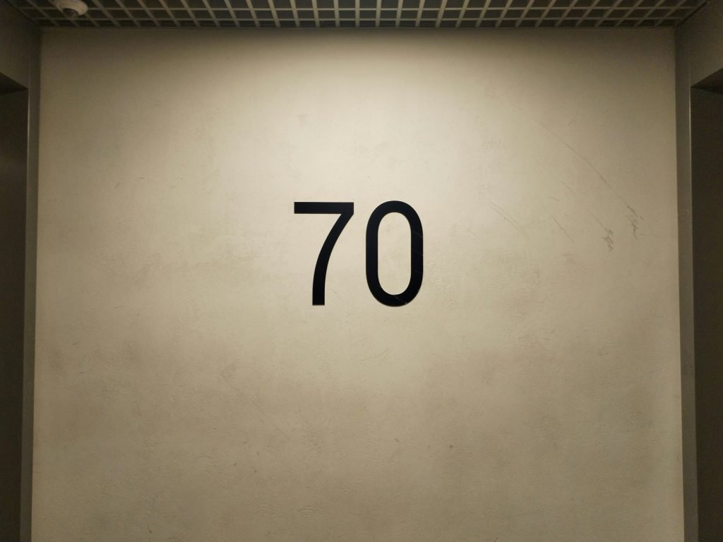 eine-weisse-wand-mit-einer-schwarzen-zahl-siebzig-darauf-TkmJIHRnkY4