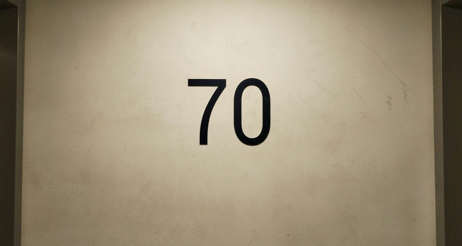 eine-weisse-wand-mit-einer-schwarzen-zahl-siebzig-darauf-TkmJIHRnkY4