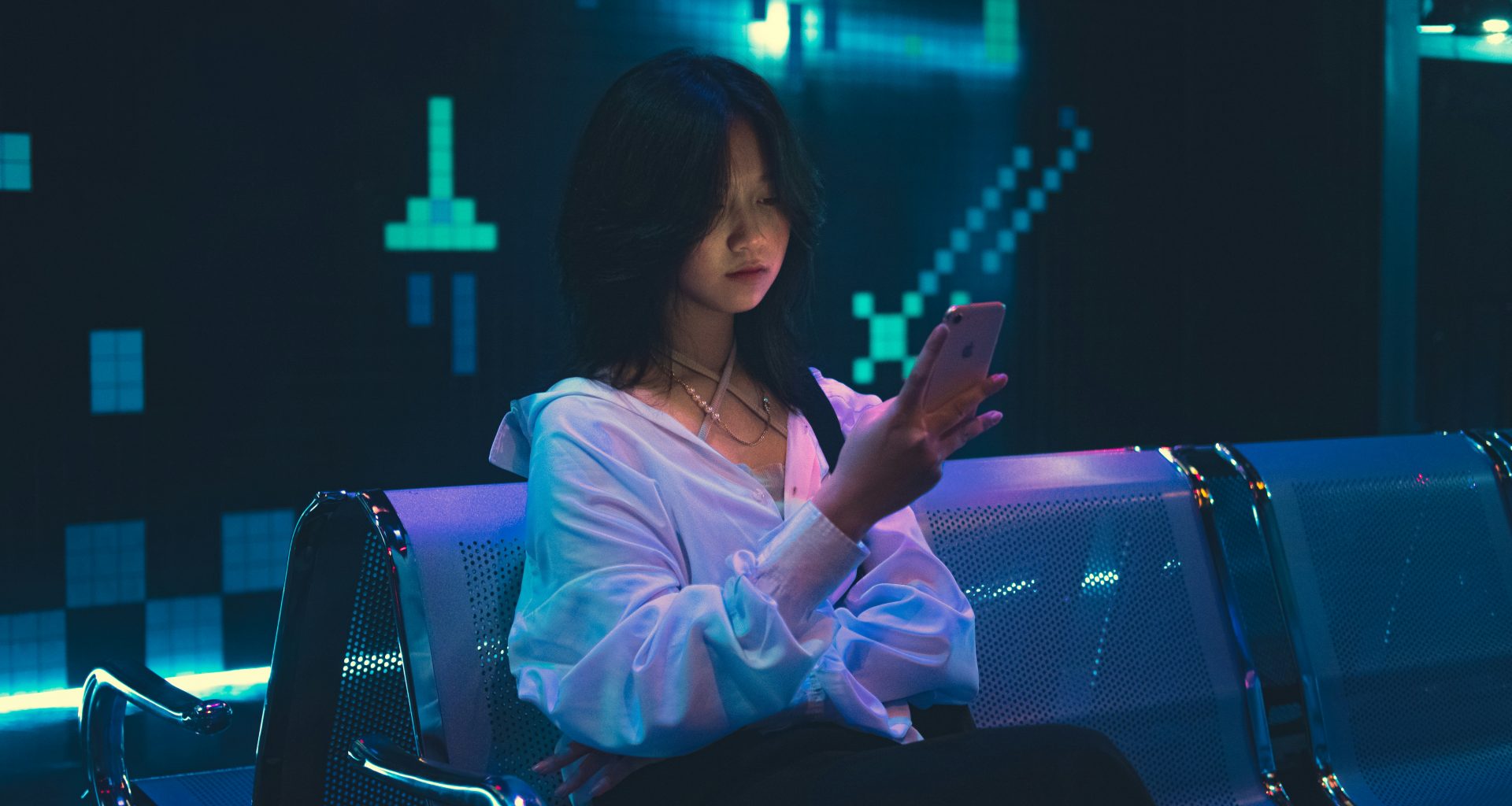 eine-frau-die-mit-einem-handy-auf-einer-bank-sitzt-DSSZYpM0V1I