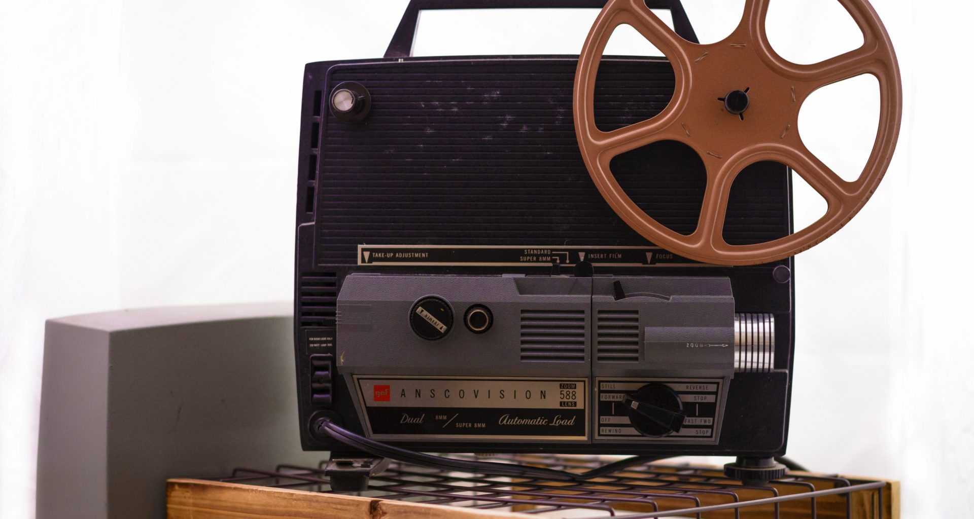 ein-alter-filmprojektor-sitzt-auf-einem-tisch-FWkYZBUs7e0