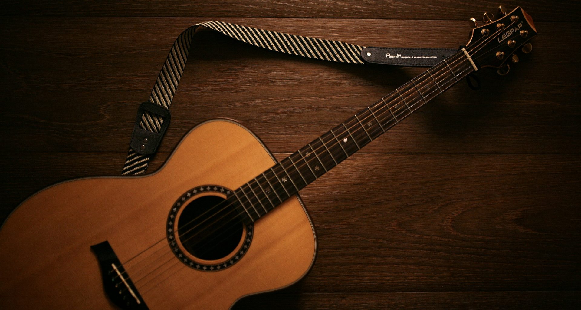 braune-akustikgitarre-auf-braunem-holzboden-b57RqS-nQ1c