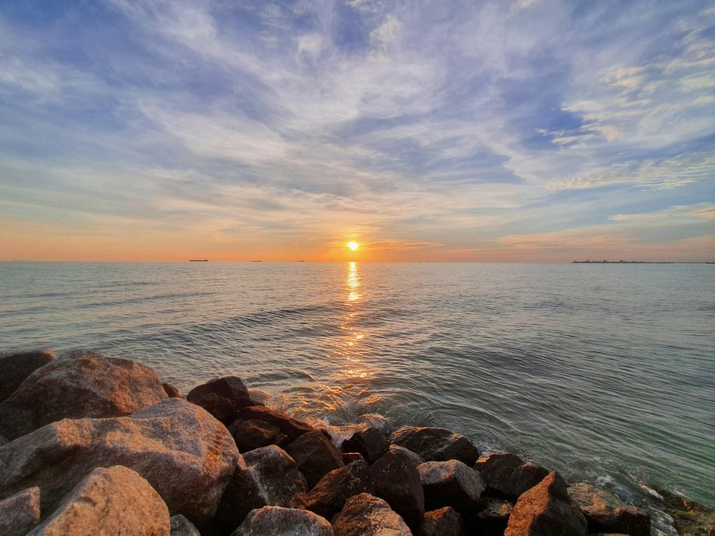 braune-und-graue-felsen-in-der-nahe-von-gewassern-bei-sonnenuntergang-KmhFdOFgxEw