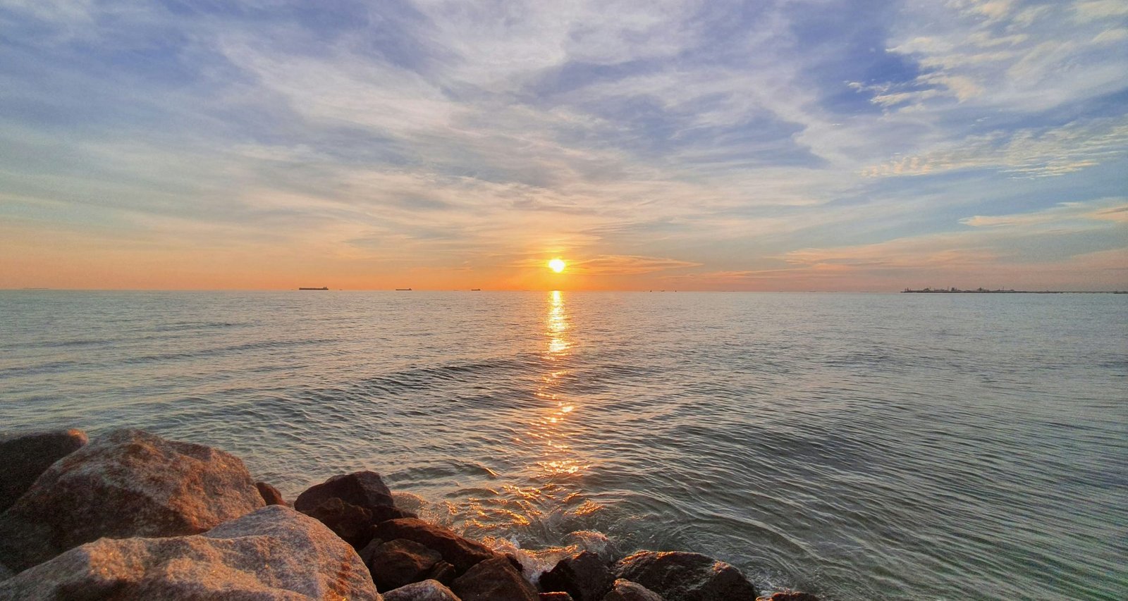 braune-und-graue-felsen-in-der-nahe-von-gewassern-bei-sonnenuntergang-KmhFdOFgxEw