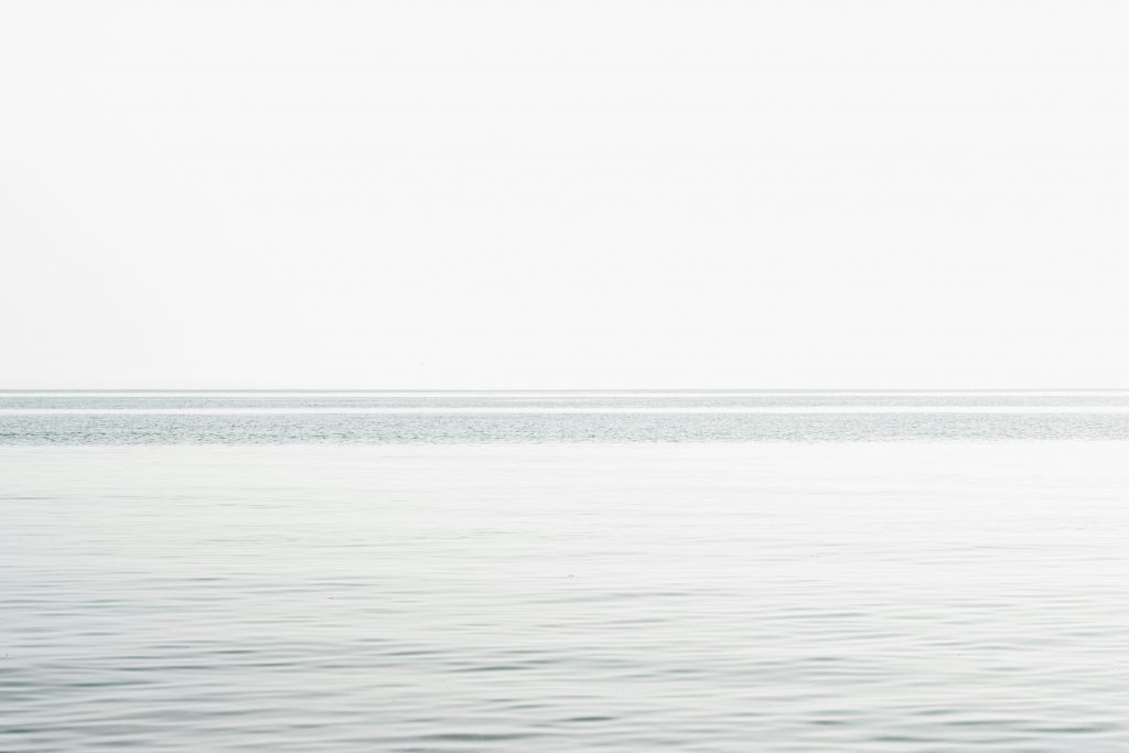 ruhiges-meer-unter-weissem-himmel-tagsuber-TRgtBr9wZDA