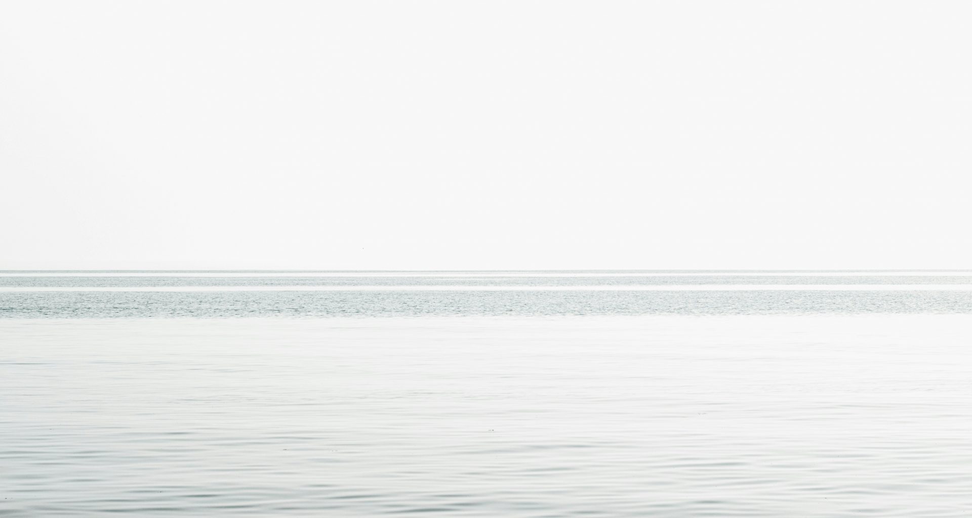 ruhiges-meer-unter-weissem-himmel-tagsuber-TRgtBr9wZDA