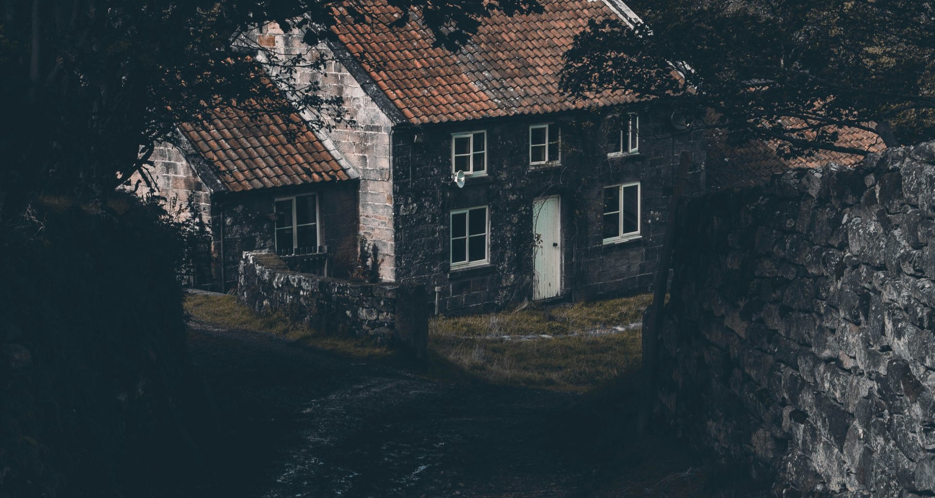 graues-haus-in-der-nahe-von-baum-und-mauer-hCotdHCBJag