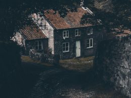 graues-haus-in-der-nahe-von-baum-und-mauer-hCotdHCBJag