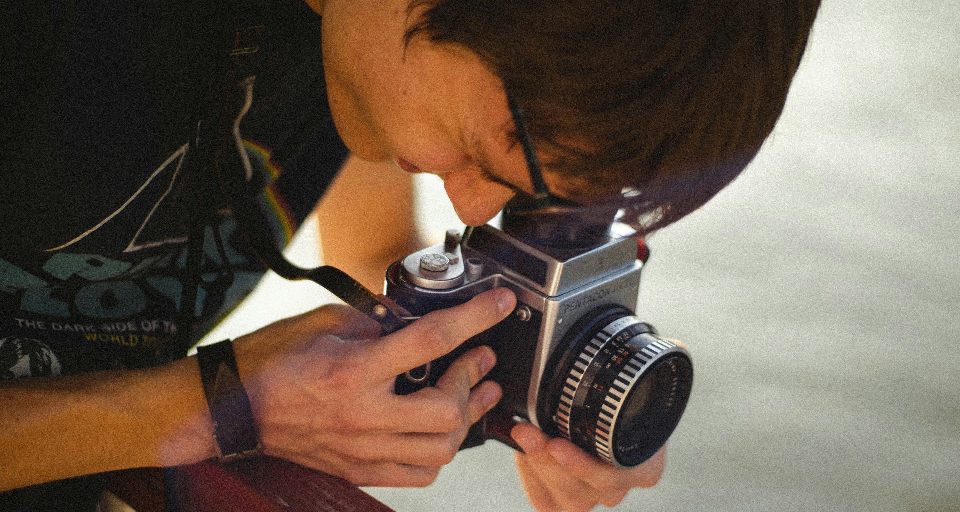 mann-in-schwarz-weissem-hemd-mit-schwarz-silberner-dslr-kamera-DAu61oUP9Vw