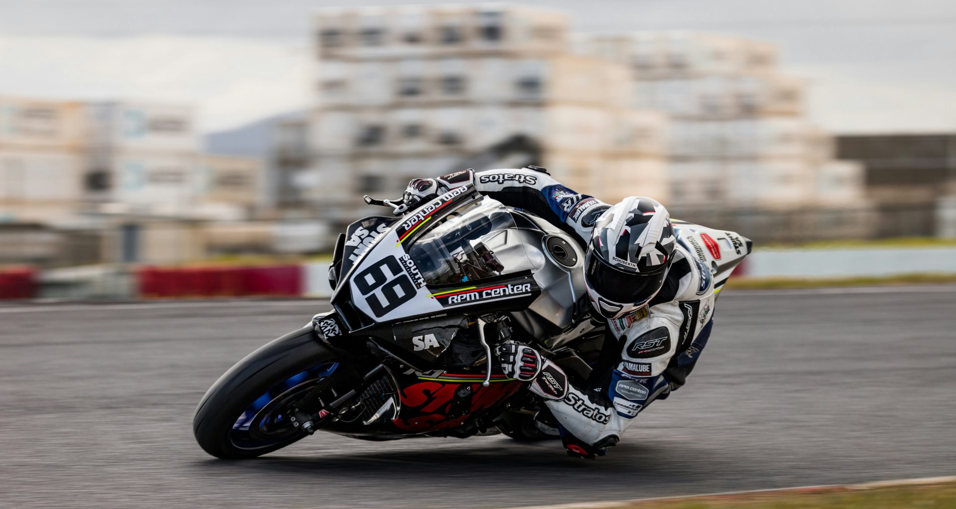 mann-im-blau-weissen-motorradanzug-fahrt-auf-schwarz-weissem-sportrad-HrznKKHgKvU