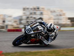 mann-im-blau-weissen-motorradanzug-fahrt-auf-schwarz-weissem-sportrad-HrznKKHgKvU