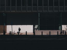 mann-zu-fuss-in-der-nahe-von-fahrrad-neben-gebaude-TzaJgKf-0U0