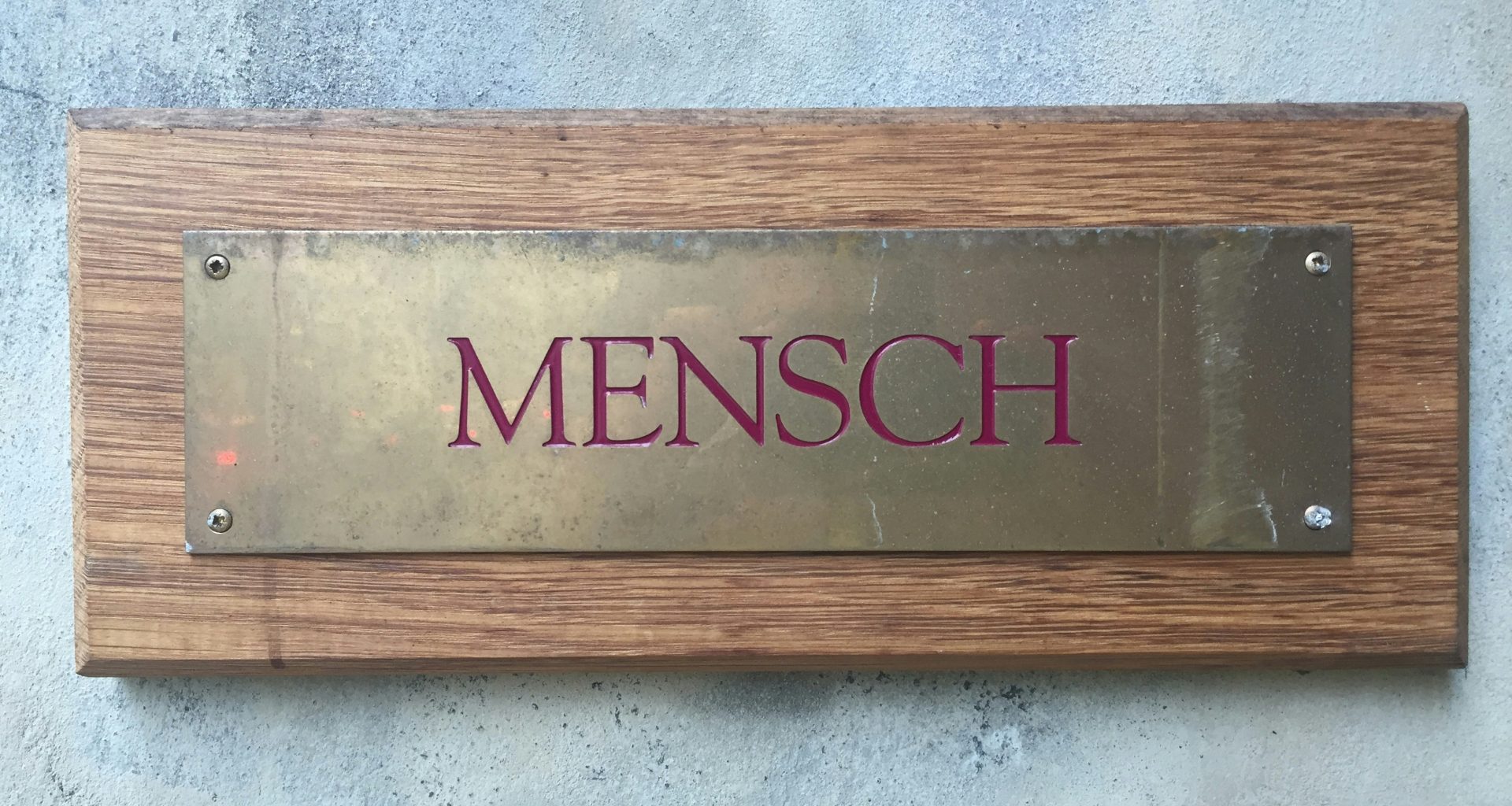mensch-messingplatte-auf-holzblock-an-der-wand-angebracht-EOQ1x-CGe-M